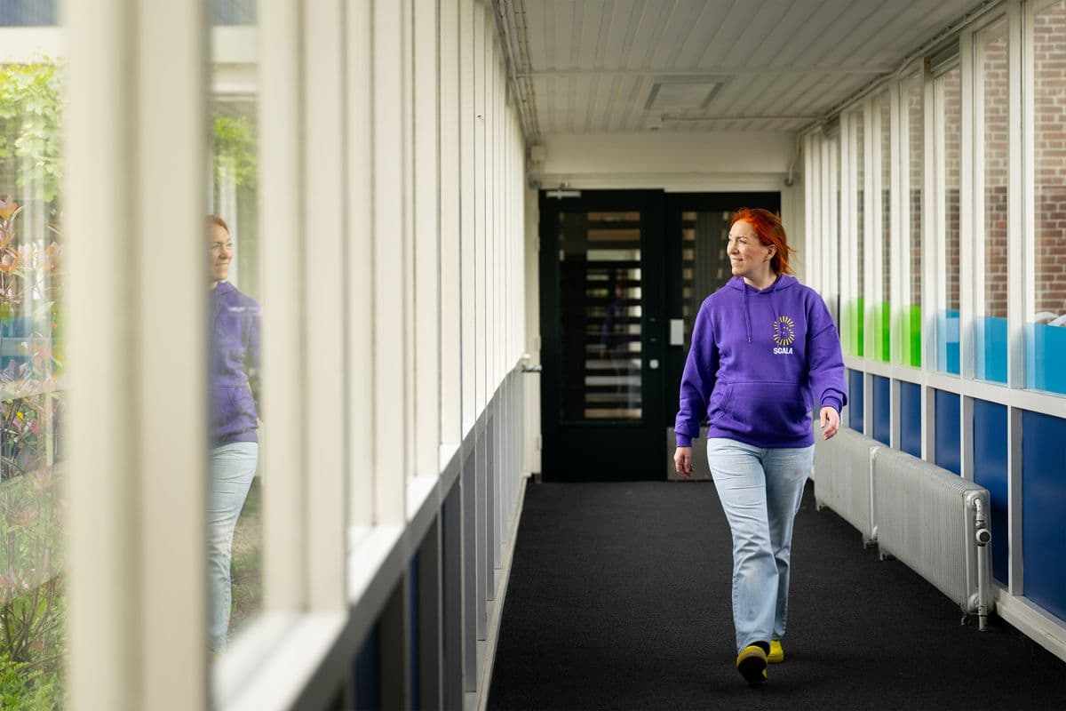 Jeugdprofessional loopt lachend door de gang van een school